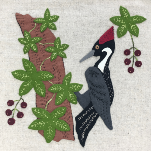 Wool Appliqué Block of wildlife quilt design by Carried Away Designs showing a gray woodpecker with red crest on a branch
