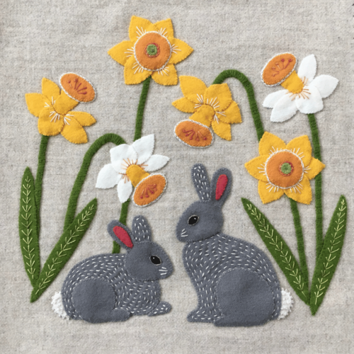 Wool Appliqué Block of wildlife quilt design by Carried Away Designs showing Two gray Bunnies sitting under yellow and white daffodils