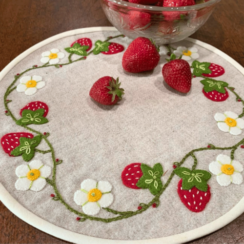 Carried Away Designs linen-colored round table mat with red strawberries and white flowers with a yellow center