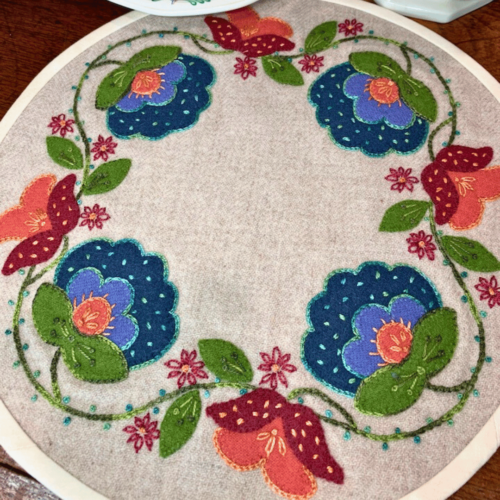 Carried Away Designs linen-colored round table mat with red and blue floral Jacobean pattern