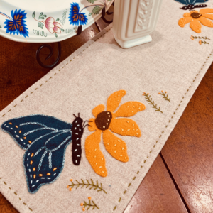 Carried Away Designs linen-colored table runner with black butterfly on yellow flower