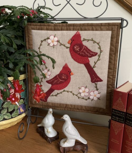 Two cardinals on tan background with brown border